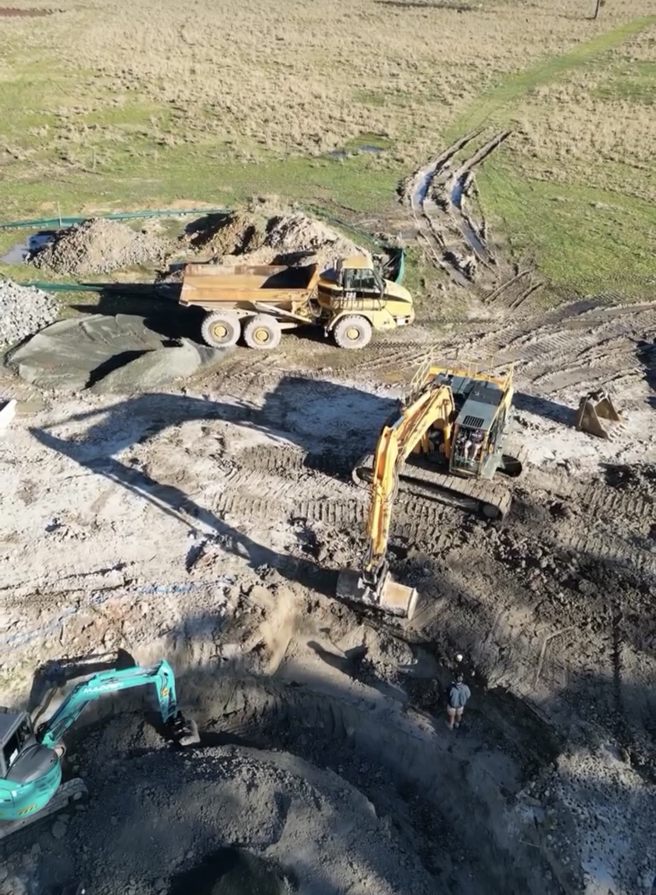 Aerial view of bulk earthworks with dump truck, Hyundai 14t excavator and teal Kobelco loading spoil on a Hawkesbury rural site