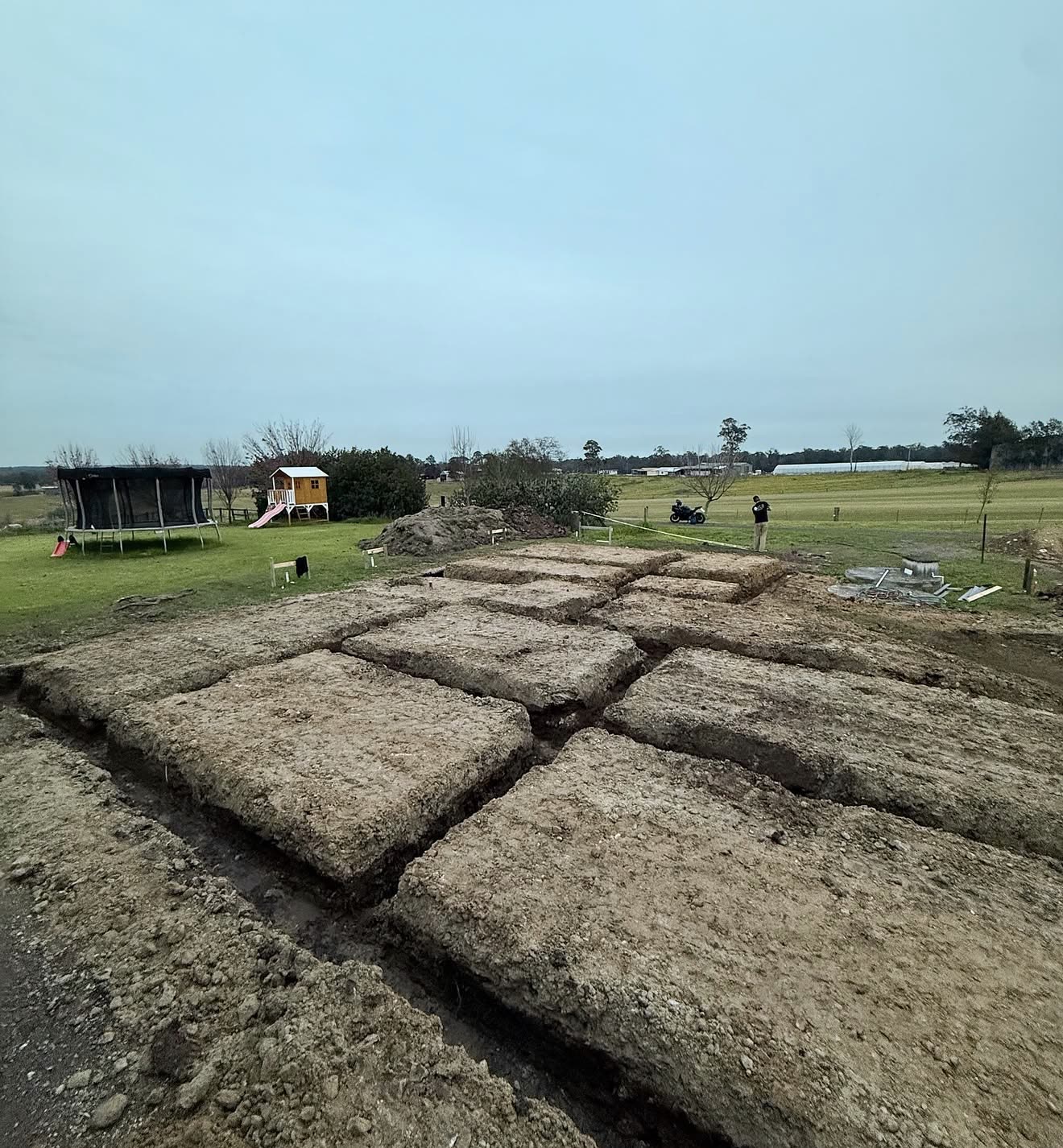 Grid of bored pier footings excavated for a new rural home at dusk
