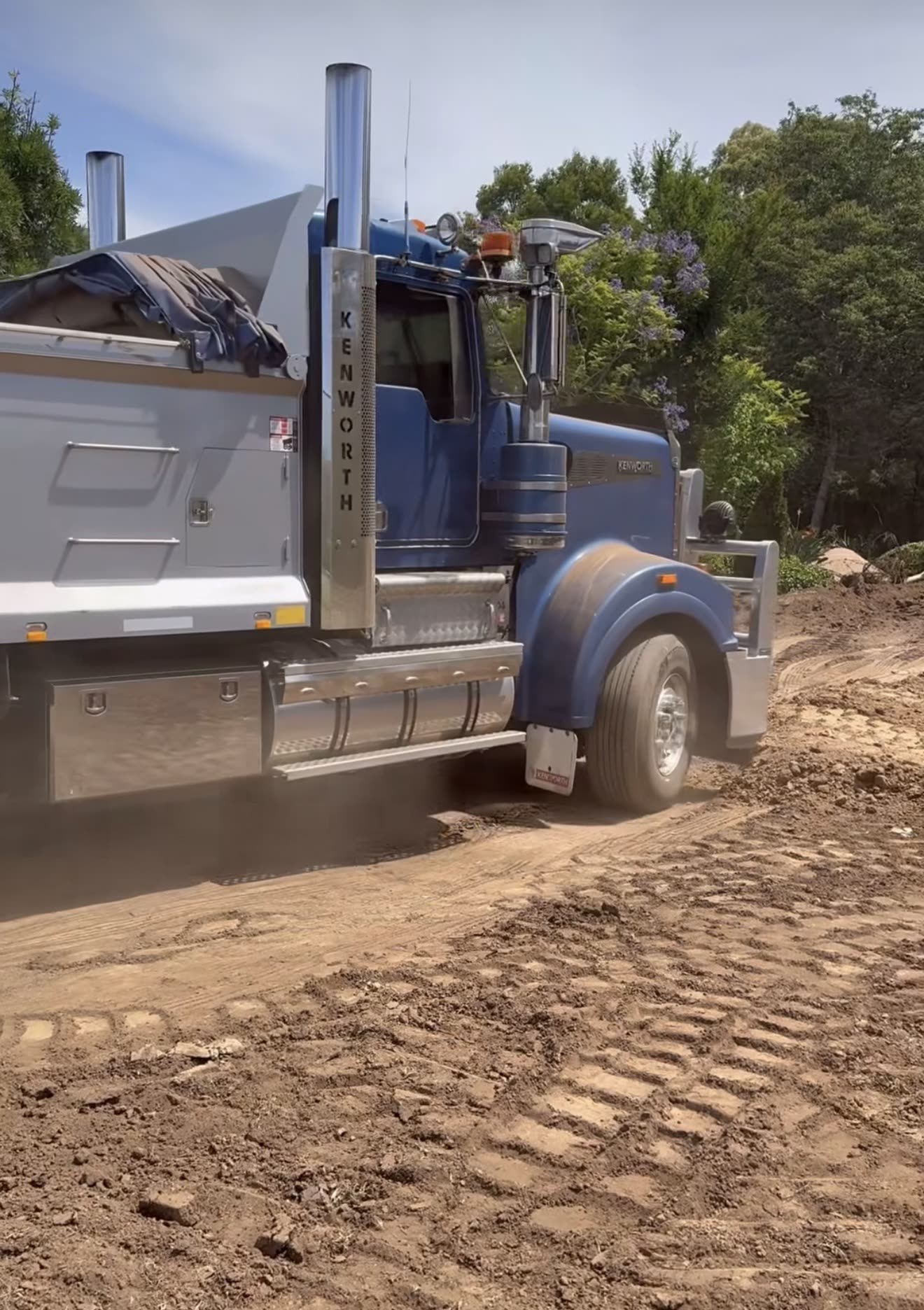 Blue Kenworth tip truck on a dirt trail hauling bulk fill