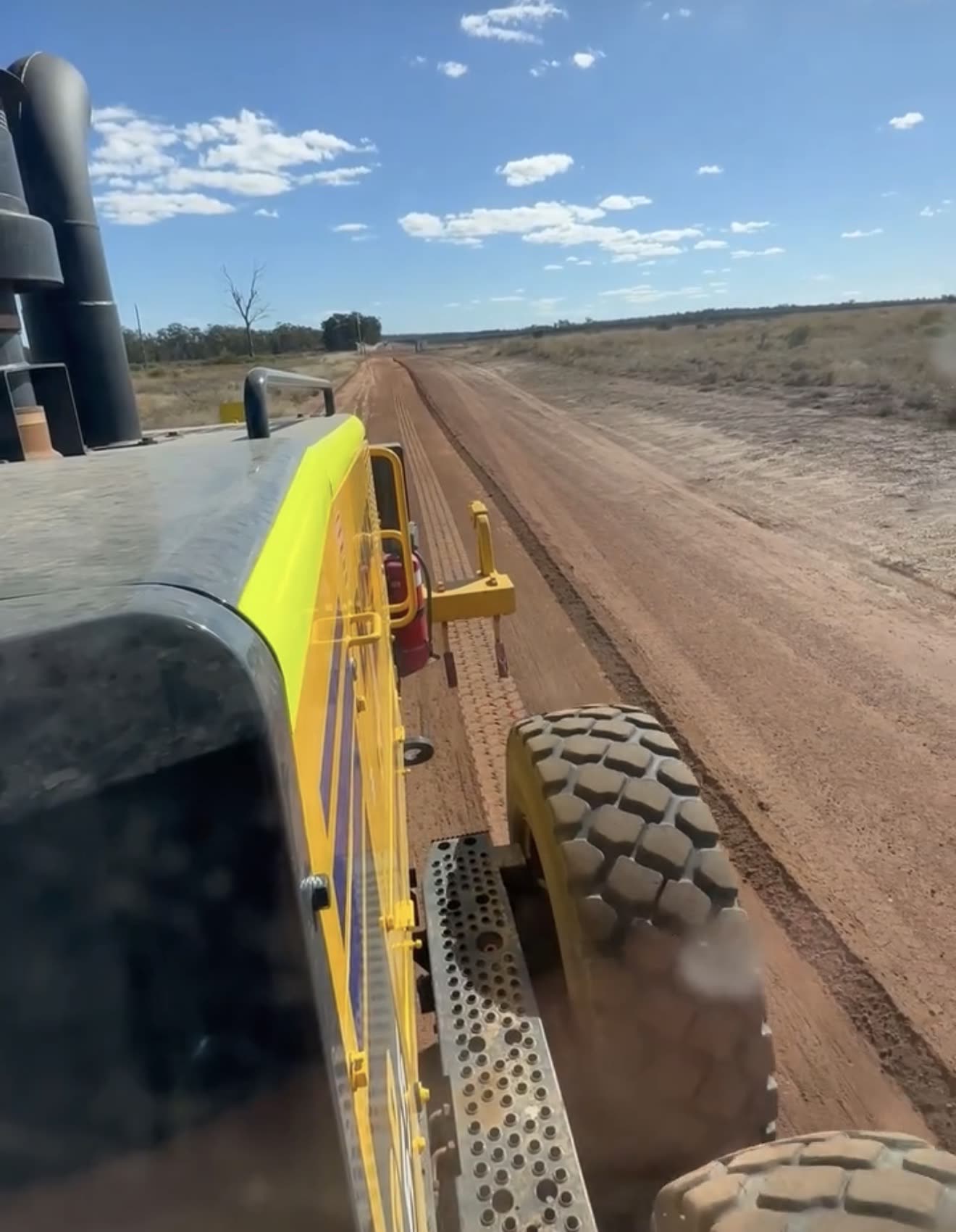 In-cab operator POV on a grader cutting a red-dirt haul road